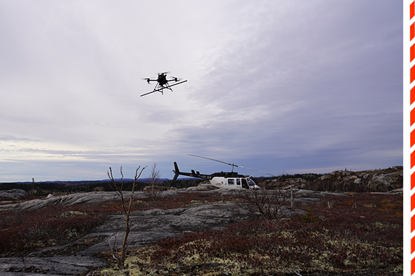 Canada Drone with Sensor Bar Payload for Mining Survey and Helicopter Below On Rocky Terrain Landscape